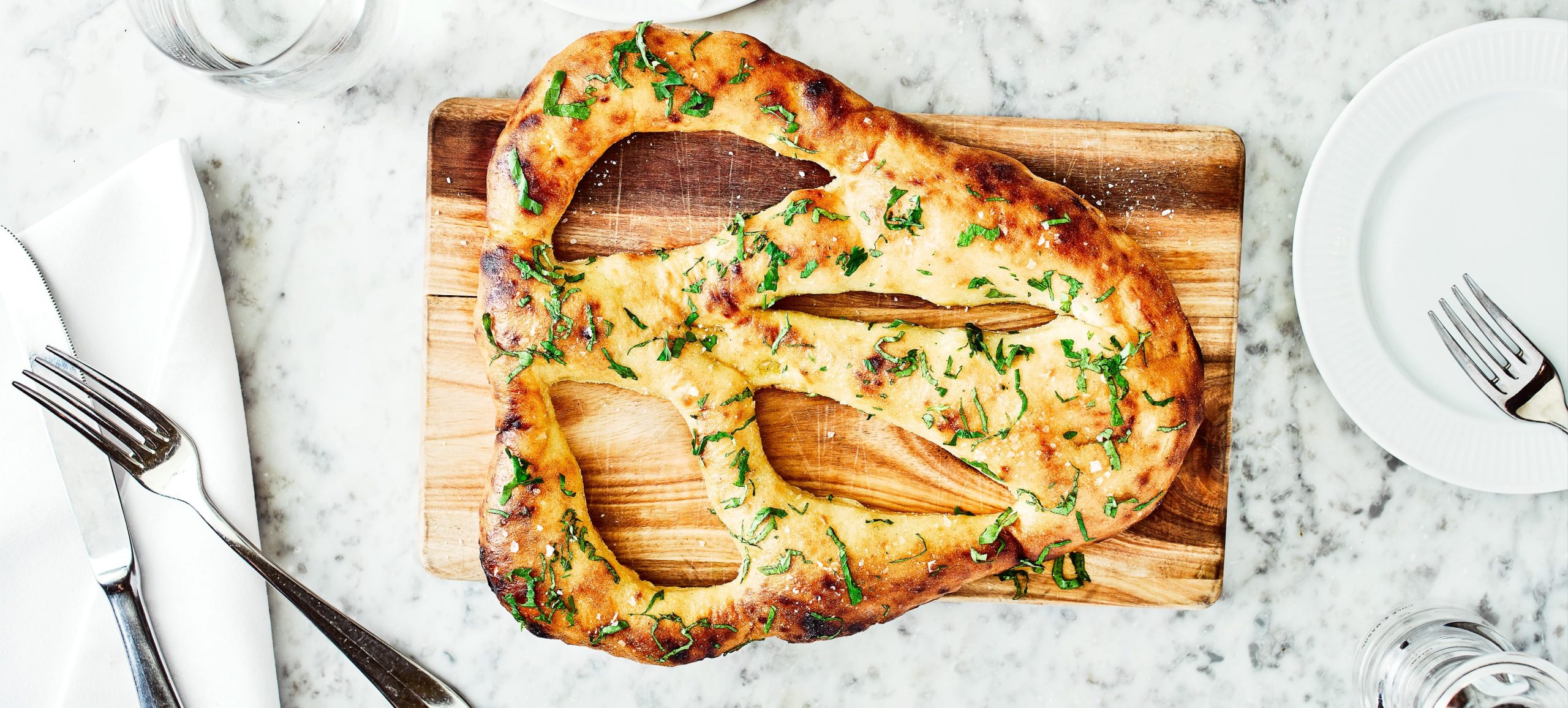 Côte, flat bread on a wooden board on a marble table