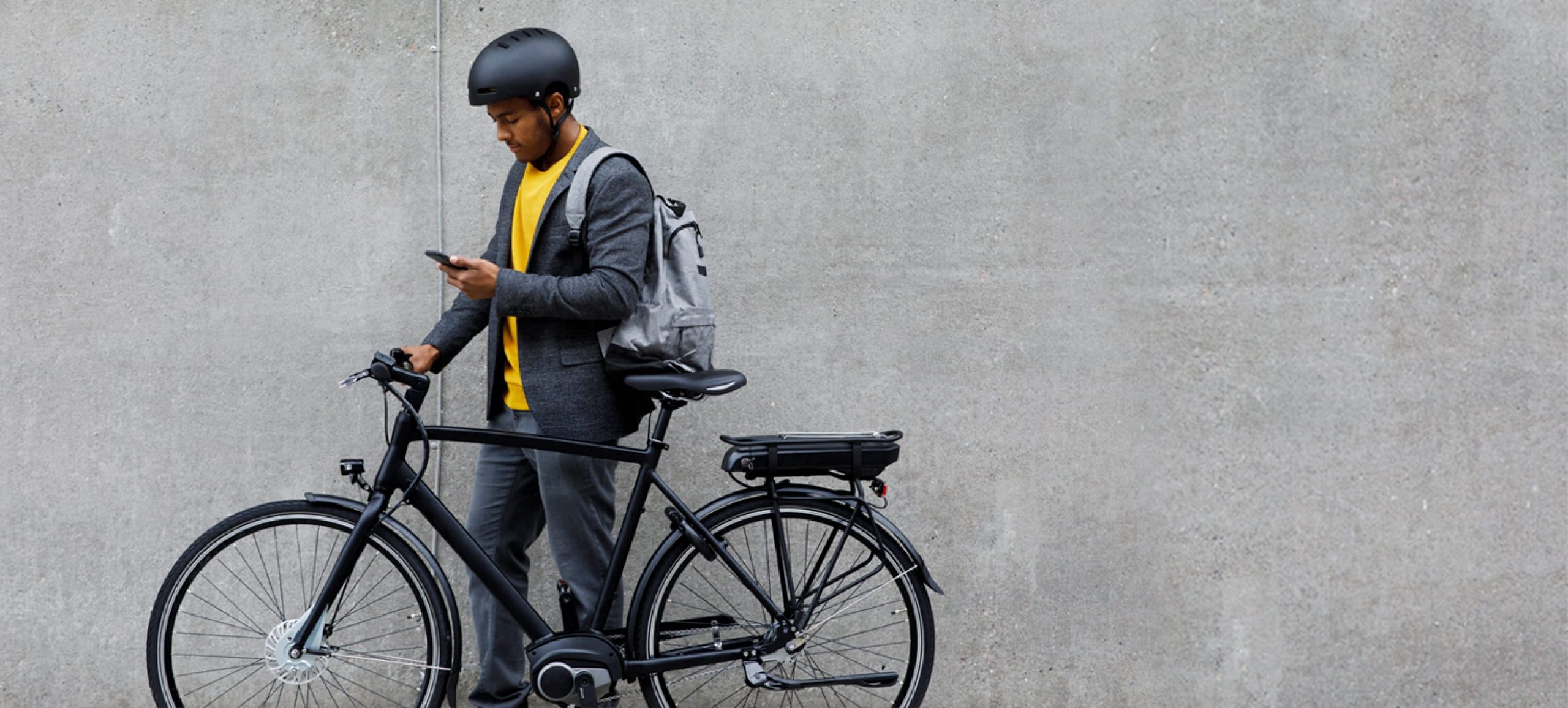 Cambridge Judge Business School, cyclist in yellow sweater looking at mobile phone